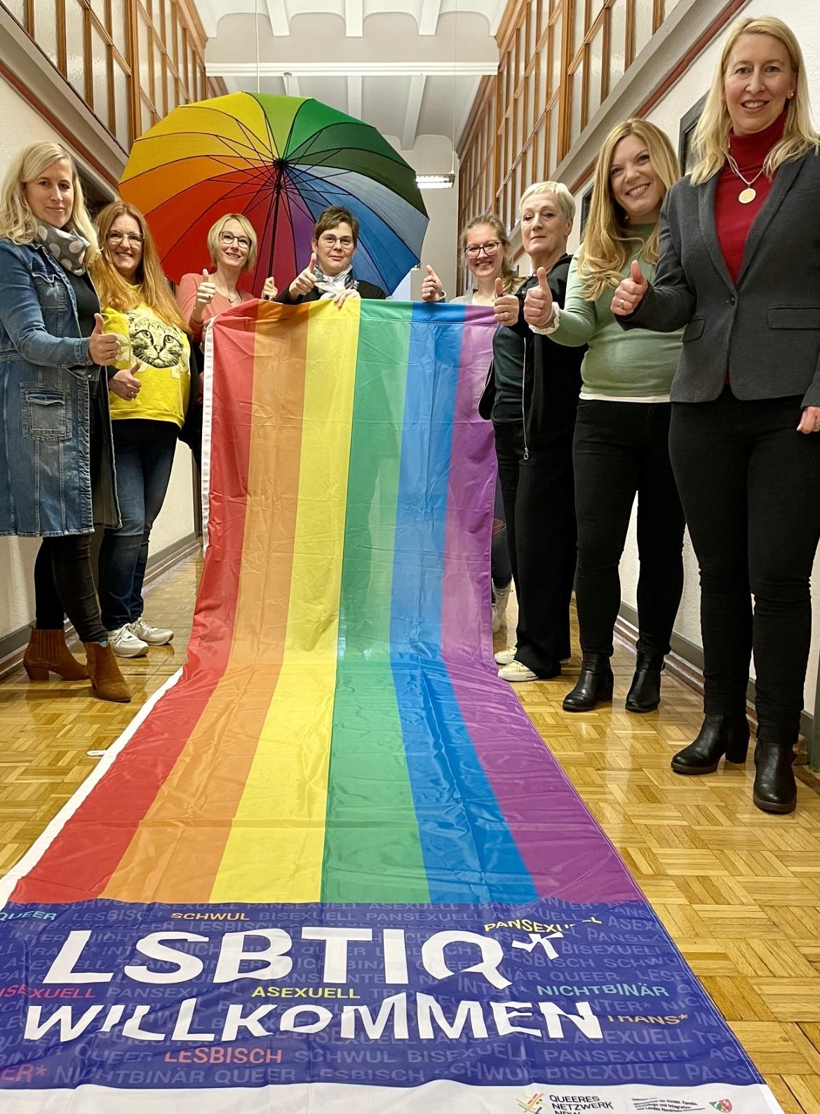 Die Gleichstellungsbeauftragten des Kreises Kleve halten eine Regenbogenflagge hoch